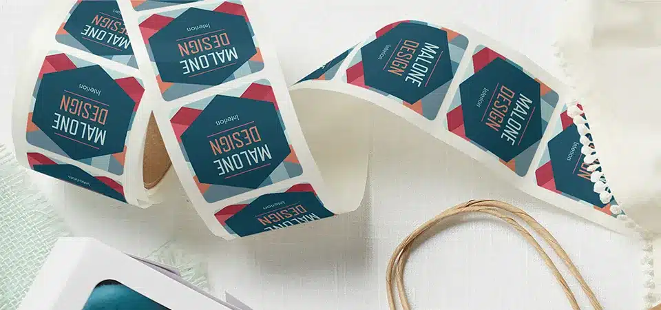 A hand applying a custom roll label to a glass jar of honey.