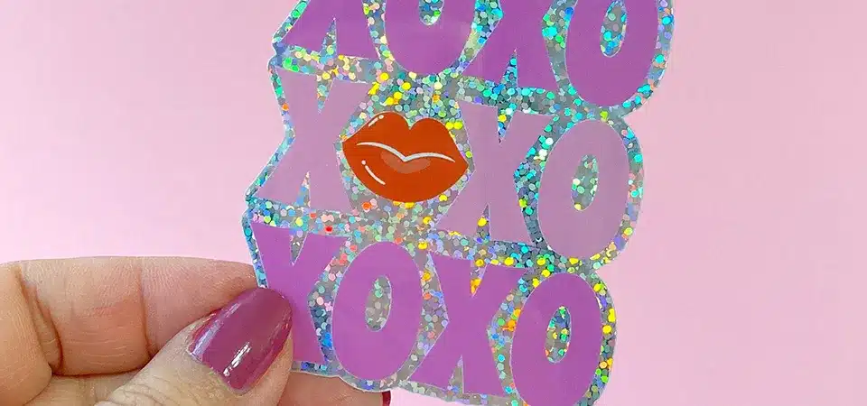 A person easily peeling a glitter sticker off a glass window in one clean piece.