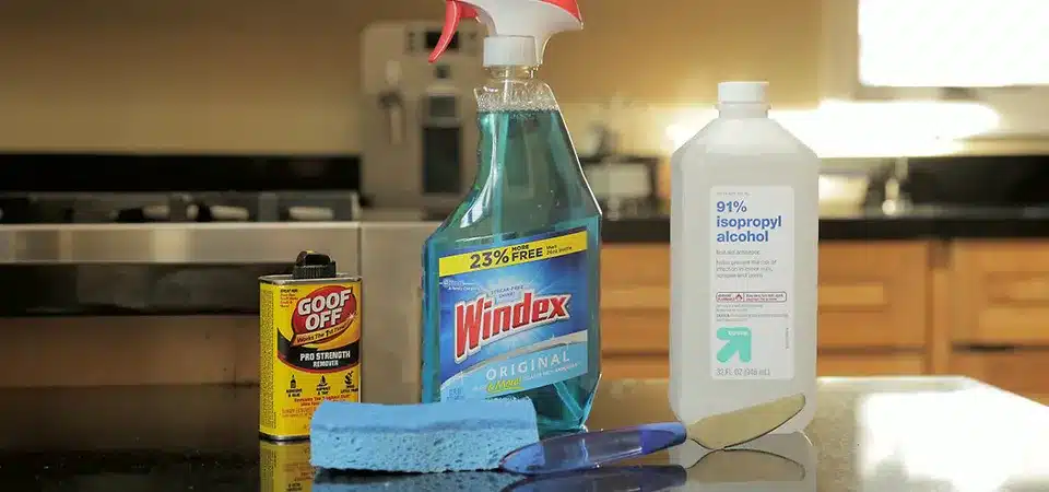 A hand spraying window cleaner on a glass window with a sticky patch.