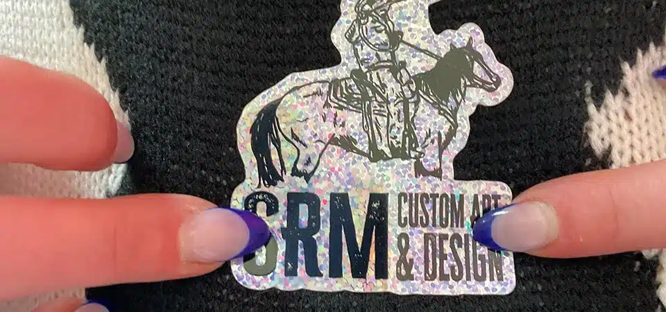A side-by-side comparison of a glitter sticker and a holographic sticker.