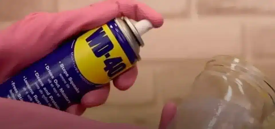 A can of WD-40 next to a glass surface where residue has been wiped clean.