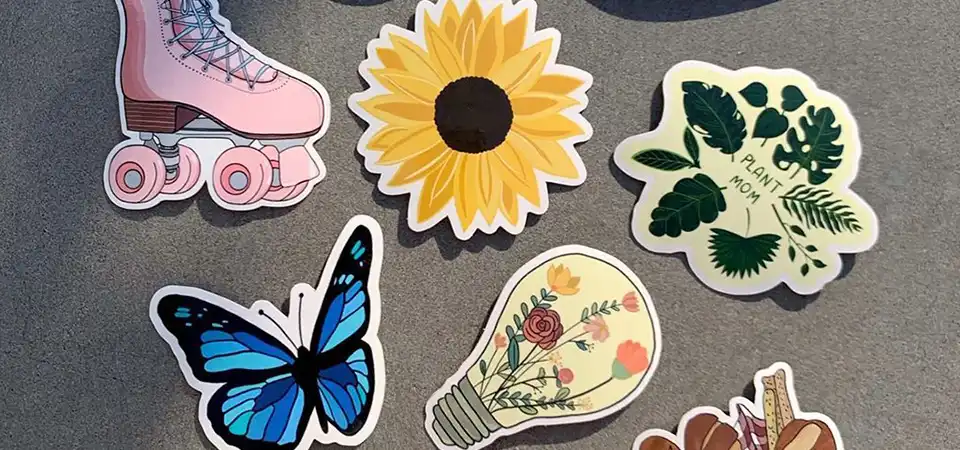 A collection of die-cut stickers in various materials: glossy, matte, holographic, and clear.