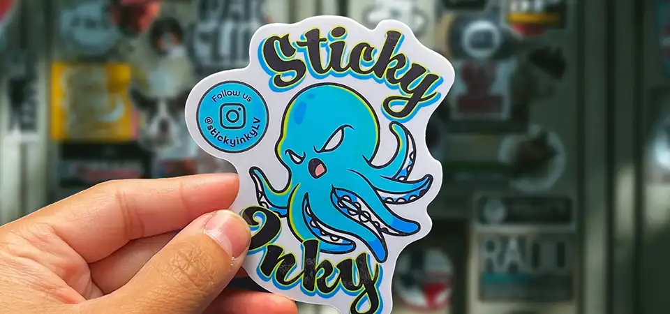 An image comparing a square sticker to a custom-shaped die-cut sticker of the same logo.