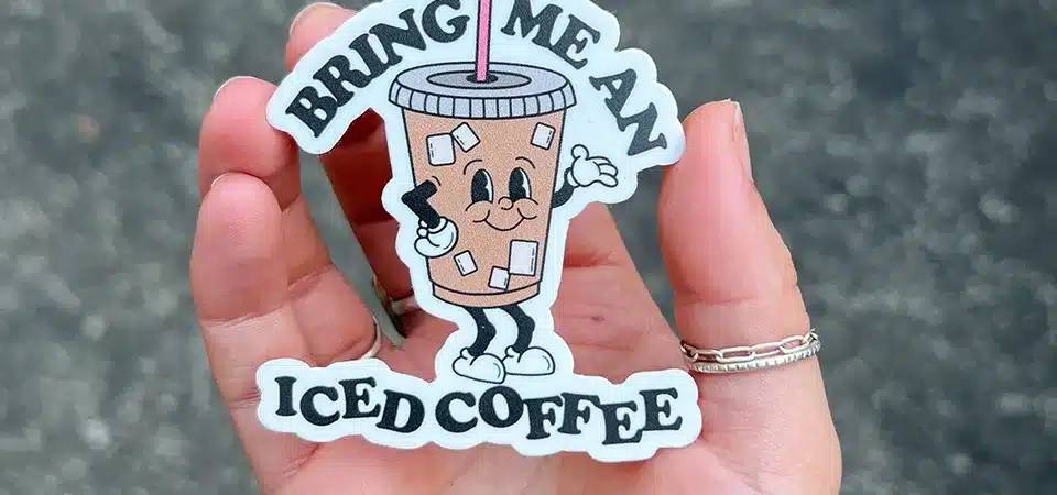 A person proudly placing a unique die-cut sticker on their laptop.