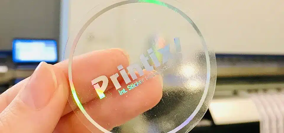 A clear vinyl sticker with a simple black logo on a glass jar of honey.