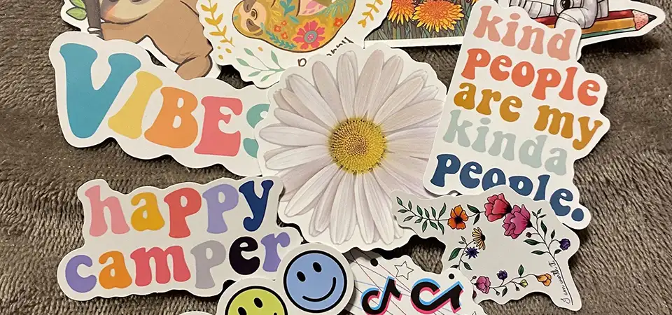 A machine laser-cutting a sheet of vinyl stickers into custom shapes.
