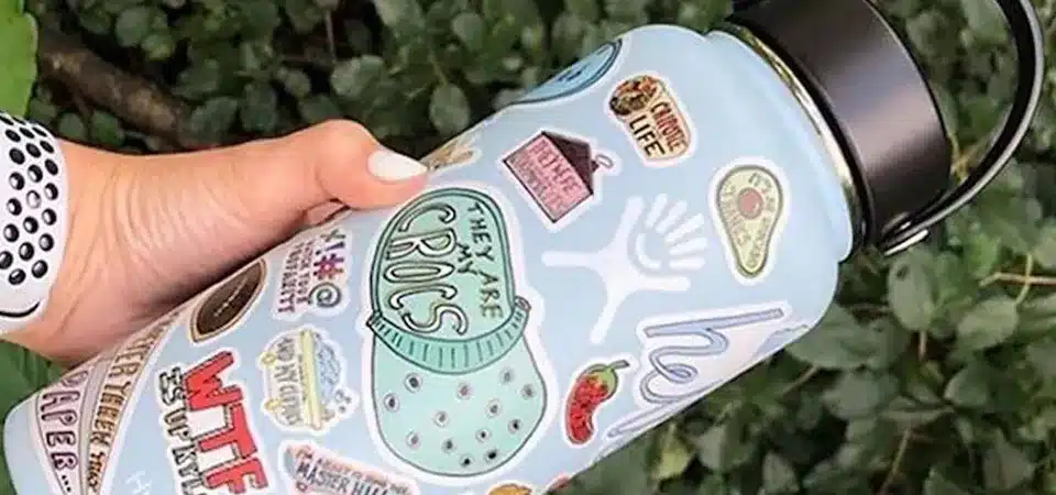 A designer on a computer screen working on a bold, circular sticker design intended for a water bottle.