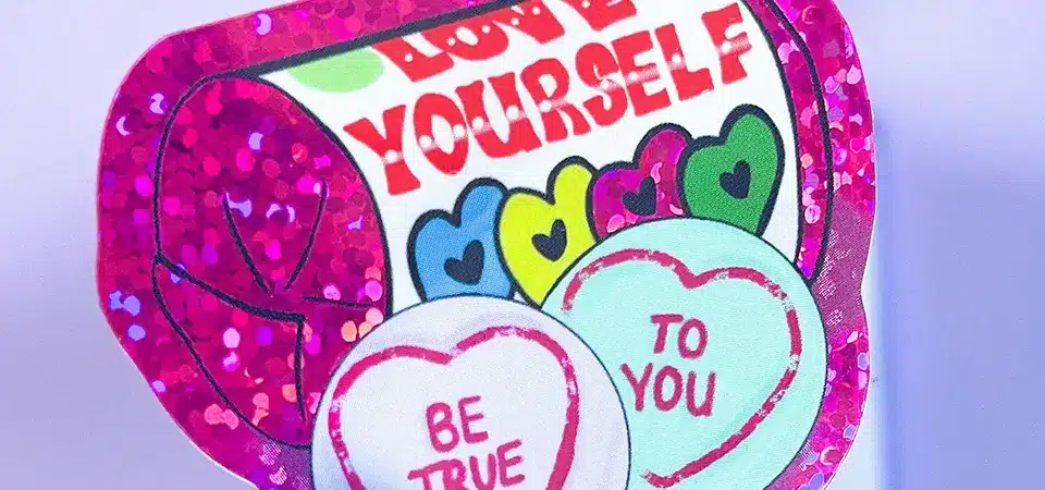 A hand holding a glitter sticker, showing no glitter residue on the fingers.