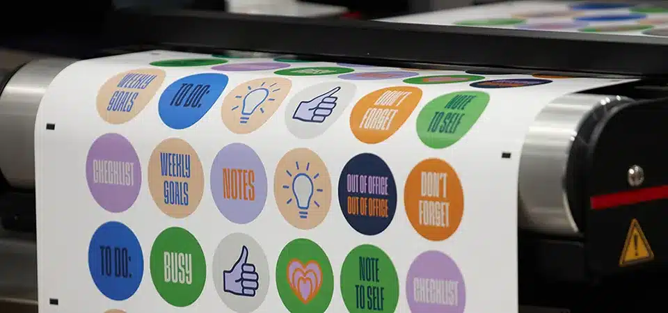 A close-up of a laser cutter precisely tracing a custom shape out of a sheet of printed vinyl stickers