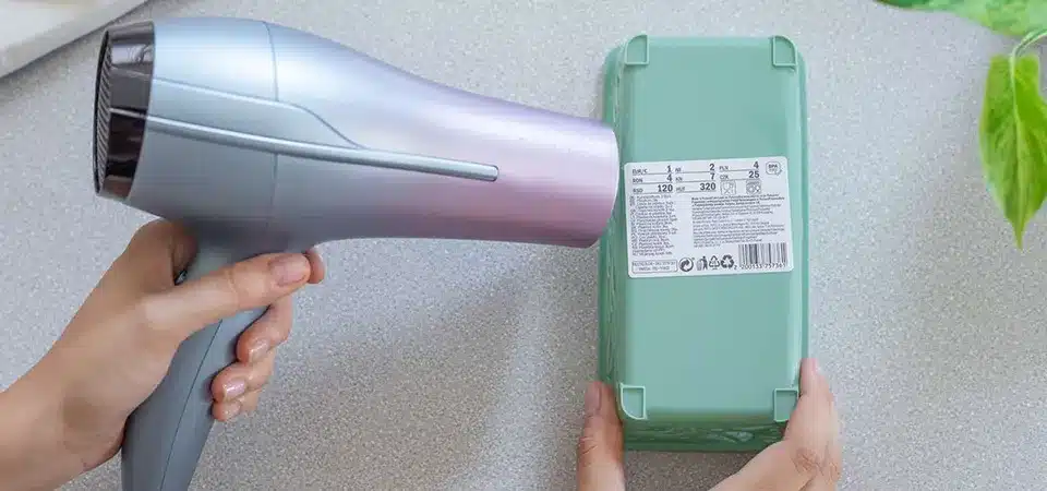 A person using a hairdryer on a peeling wall decal