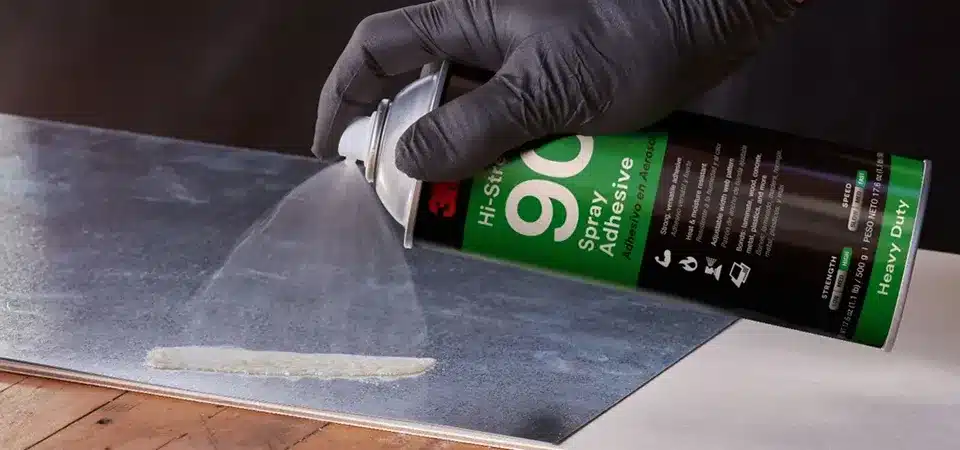 A can of 3M Super 77 spray adhesive next to a sticker on wax paper