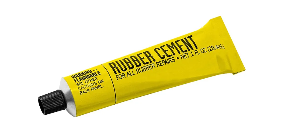 A jar of rubber cement and a brush next to a paper sticker