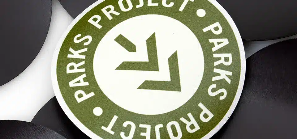 A hand neatly applying a circular sticker to a small, round magnet button