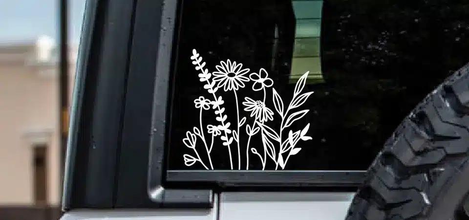 A close-up of a vinyl vehicle sticker's edge and a vehicle magnet's edge