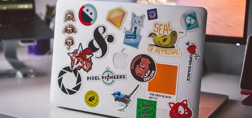 A person moving a reusable sticker from a laptop to a water bottle