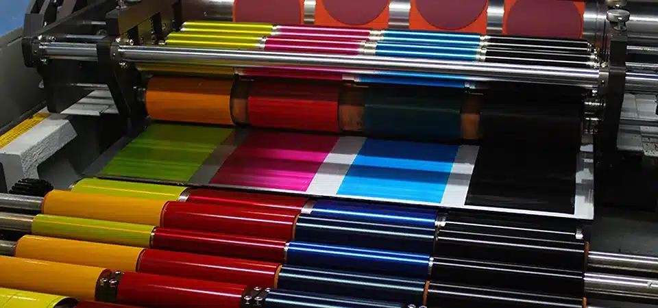 A staff member feeding individual sheets into a press vs. a massive roll of paper on a web press
