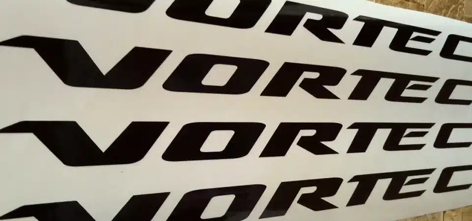 Cast Vinyl vs Calendered Vinyl A side-by-side comparison showing cast vinyl conforming to a curve and calendered vinyl on a flat surface