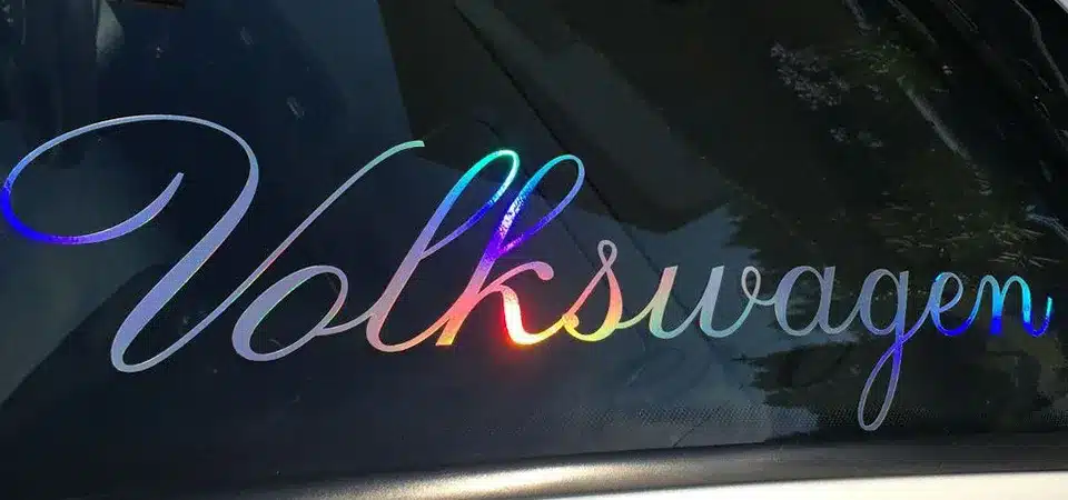 A hand peeling back transfer tape at a sharp angle, leaving perfectly applied vinyl letters on a mug