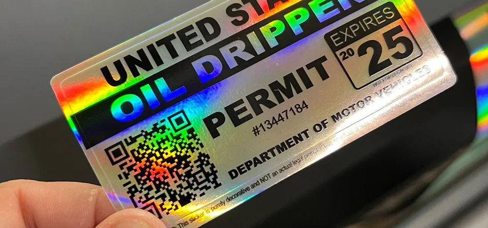 A person using a hair dryer and plastic scraper to remove a car decal