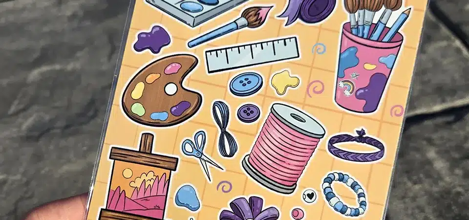 A sticker sheet themed around hobbies, showing books, gaming controllers, and art supplies