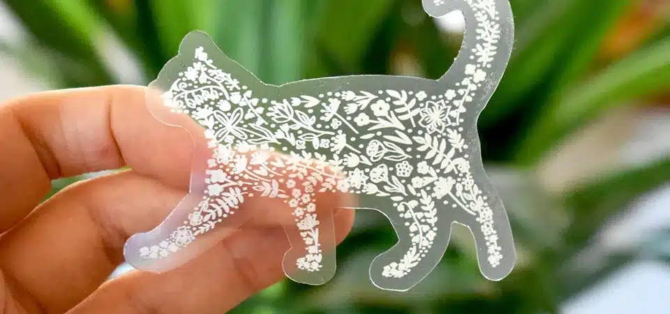 A hand smoothly applying a cold laminate sheet over a printed sheet of clear vinyl stickers