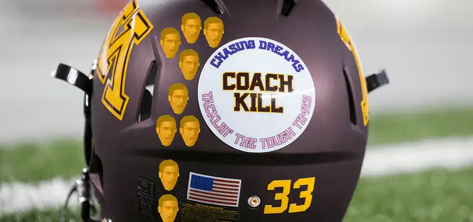 A coach handing a small award sticker to a football player in a locker room