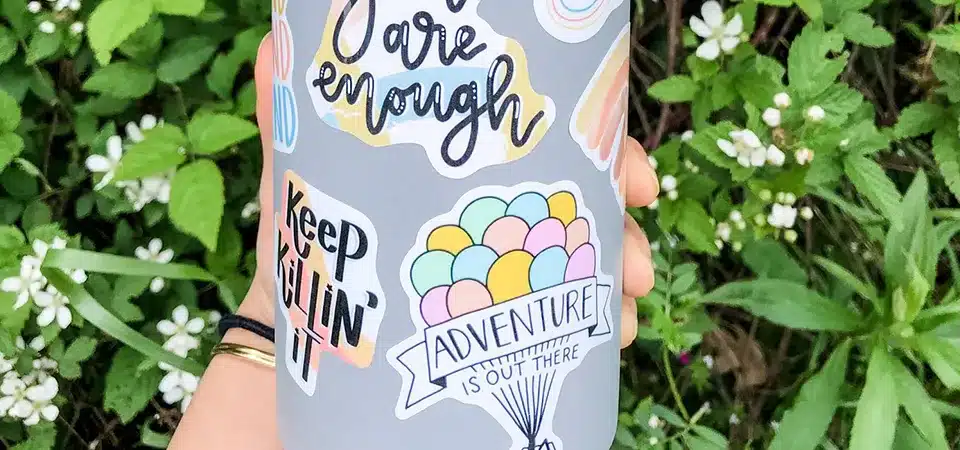 A large-format digital printer producing a colorful sheet of vinyl stickers