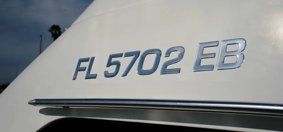 A flat lay of tools for boat sticker removal: heat gun, plastic scrapers, adhesive remover, and microfiber towels