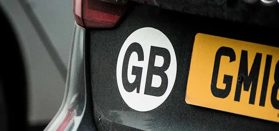 A photo showing a new UK sticker placed next to an old, faded GB sticker