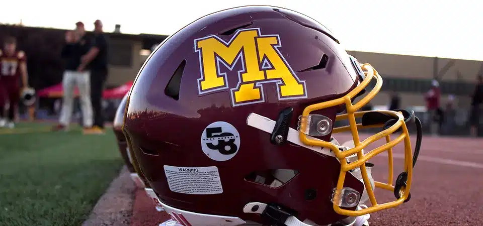 A high-quality, custom-shaped vinyl sticker being held up to a football helmet