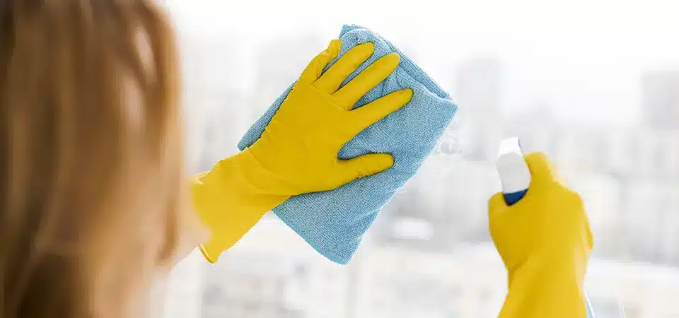 A hand wiping a window with a cloth soaked in rubbing alcohol