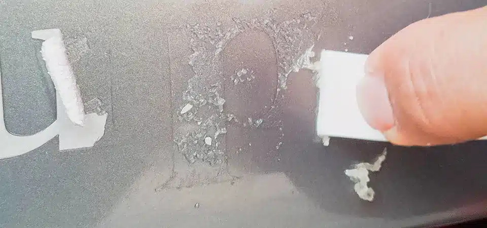 A small bowl with a paste made of baking soda and oil, with a finger showing its consistency