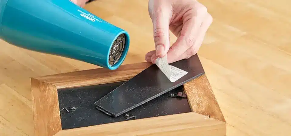 A hairdryer being pointed at a sticker on a wooden cabinet door