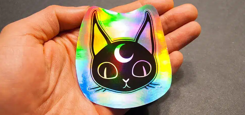 Tools for Making Holographic Stickers A workspace laid out with holographic sticker paper, a printer, and scissors