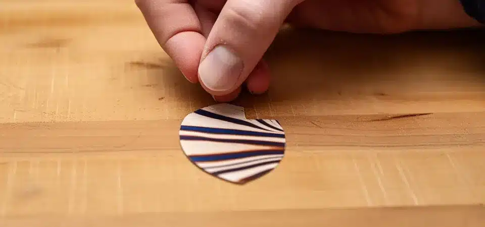 A cotton ball soaked in vegetable oil being applied to sticky residue on a wooden table