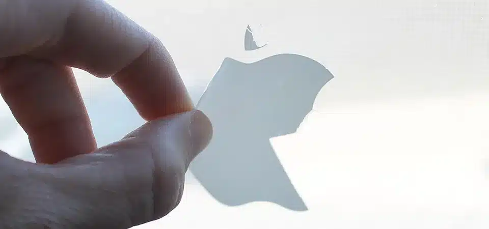 A hand gently peeling a sticker off the corner of a mirror at a low angle