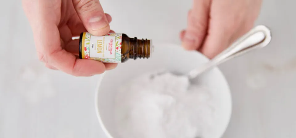 A small bowl with a paste of coconut oil and baking soda next to a plastic bottle with a stubborn sticker