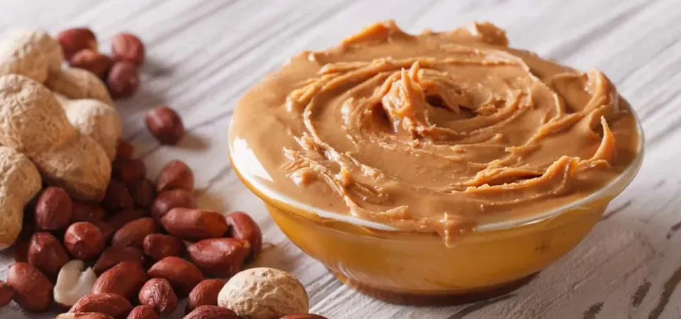 A dab of peanut butter sitting on top of a sticky residue on a plastic container