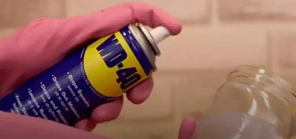 A can of WD-40 next to a plastic tool case with thick, gummy sticker residue being wiped off
