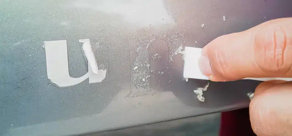 Applying WD-40 to a stubborn sticker on metal A can of WD-40 being sprayed on a very old bumper sticker on a metal surface