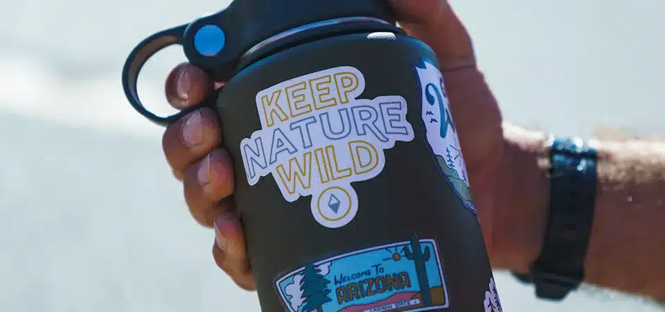 A split-screen image of a water bottle with a glossy sticker on one side and a matte sticker on the other