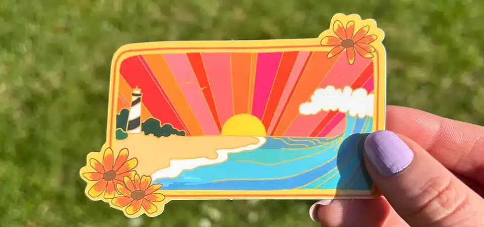 A hand gently washing a sticker-covered thermos in a kitchen sink