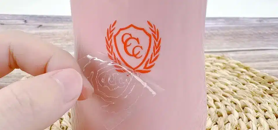 A hand using a squeegee from the center out to apply a sticker smoothly