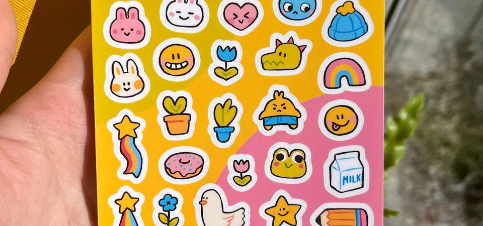 A hand carefully loading a sheet of glossy sticker paper into an inkjet printer