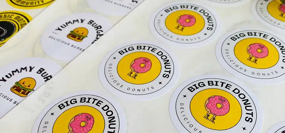 A worker rapidly applying labels to a line of candle jars using a sticker sheet