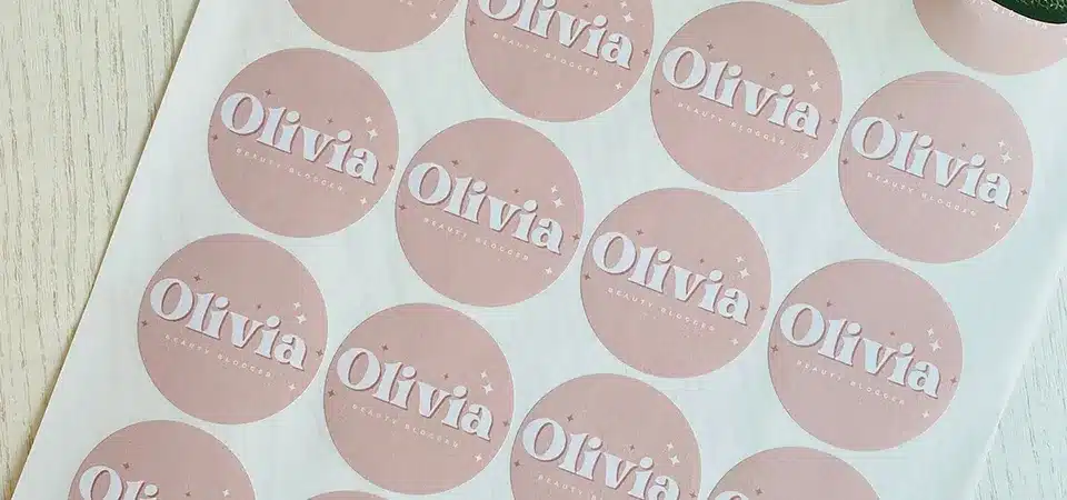 Close up of a hand peeling a kiss-cut label from a sheet showing the matrix removed