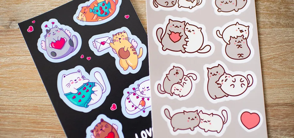 A flat lay of essential sticker-making tools: sticker paper, a ruler, scissors, and a craft knife