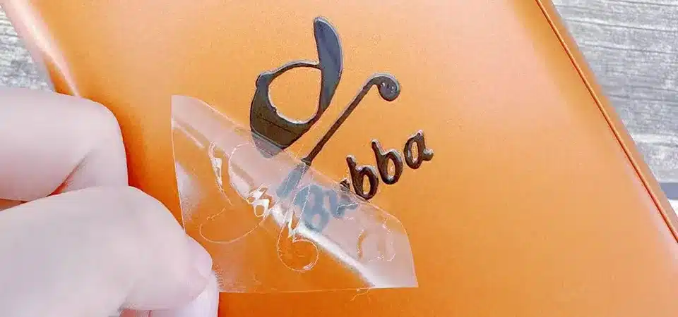 A flat lay of tools for sticker application: squeegee, masking tape, measuring tape, alcohol, and a cloth