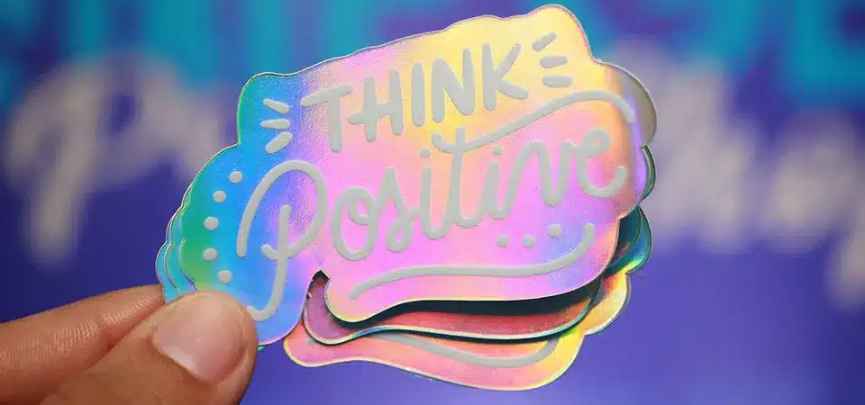 Brightly colored holographic logo sticker on a skateboard