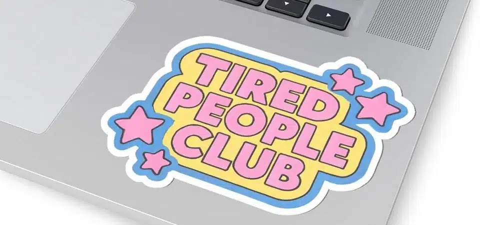 A laptop covered in colorful stickers on a coffee shop table